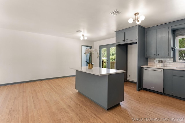 kitchen featuring stainless steel dishwasher, decorative backsplash, light hardwood / wood-style flooring, and gray cabinetry