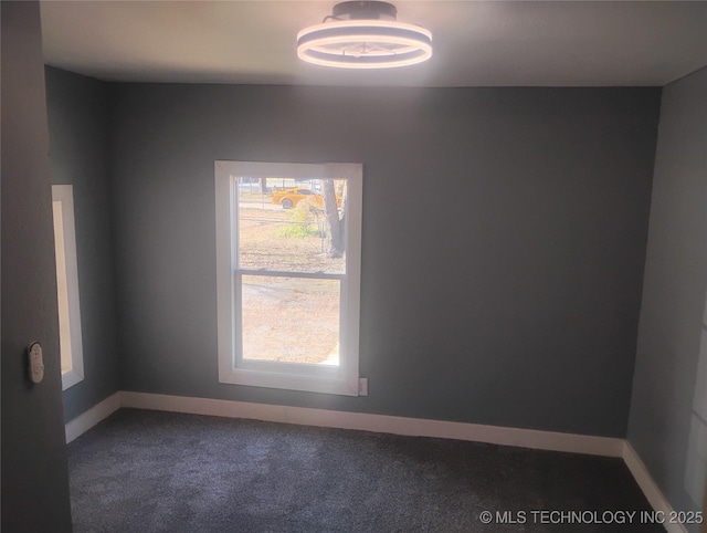 empty room featuring plenty of natural light and dark carpet