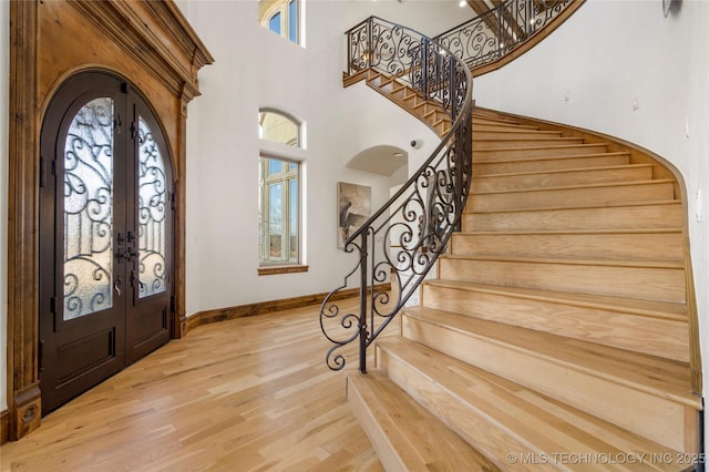 foyer with hardwood / wood-style flooring, a high ceiling, french doors, and a healthy amount of sunlight