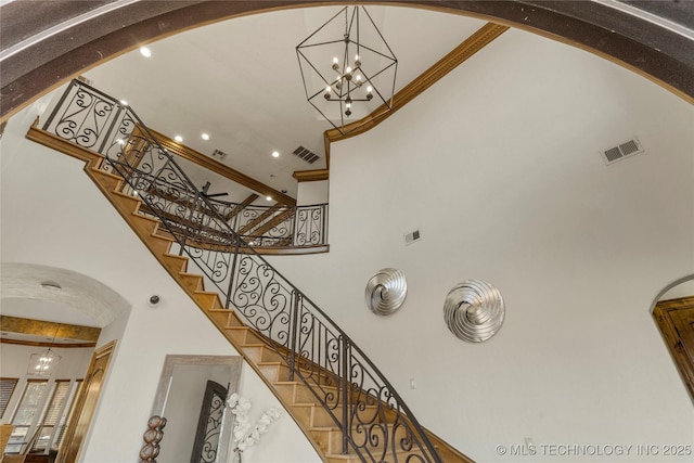 stairway with a high ceiling and a notable chandelier