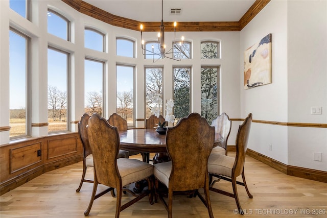 dining space with light wood-type flooring, a chandelier, and crown molding