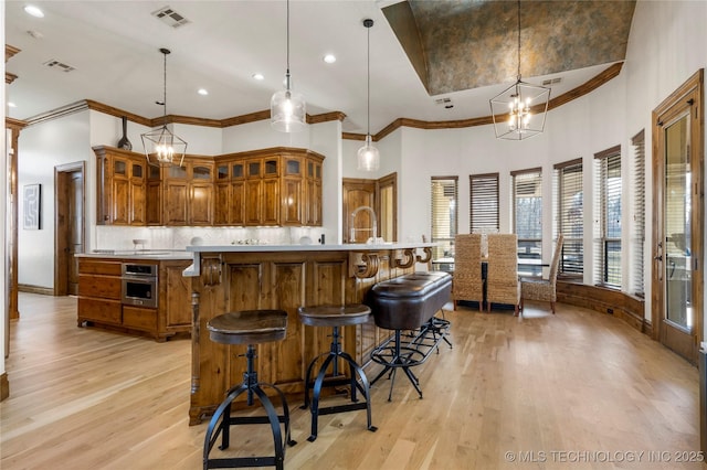 kitchen featuring a kitchen bar, light hardwood / wood-style floors, tasteful backsplash, a chandelier, and decorative light fixtures