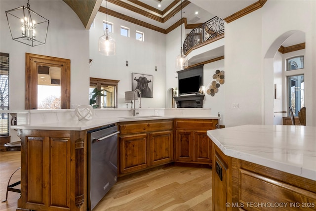 kitchen featuring decorative light fixtures, sink, stainless steel dishwasher, light hardwood / wood-style flooring, and crown molding