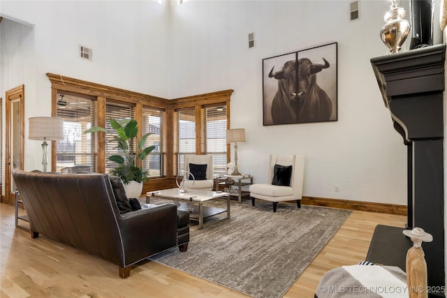 living room with light wood-type flooring and a towering ceiling