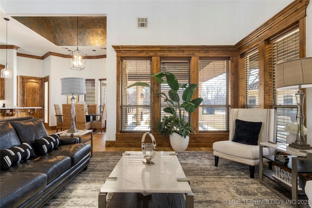 living room featuring dark wood-type flooring, crown molding, and an inviting chandelier