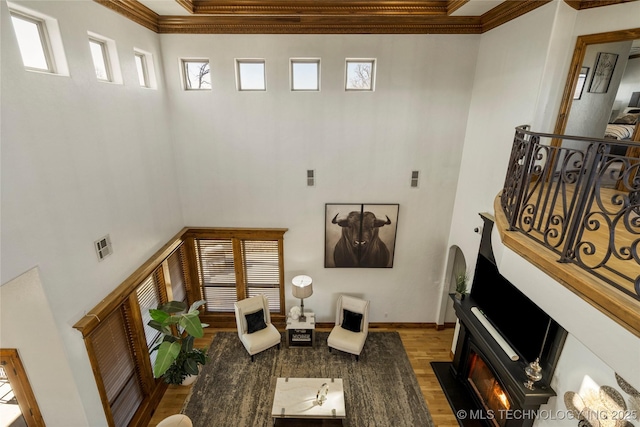 living room featuring wood-type flooring, a high ceiling, and crown molding