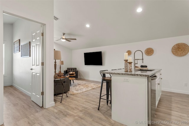 kitchen with sink, a center island with sink, light hardwood / wood-style flooring, and light stone counters