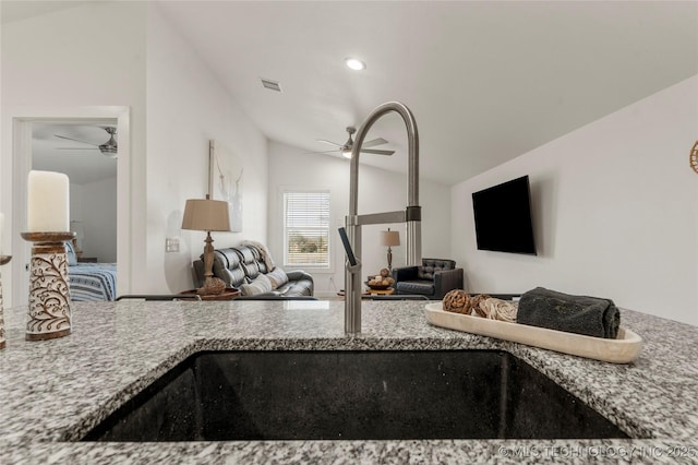 kitchen with light stone counters, lofted ceiling, and ceiling fan