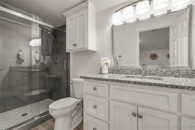 bathroom with vanity, toilet, hardwood / wood-style floors, and a shower with shower door