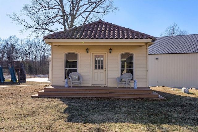 back of house with a playground and a lawn