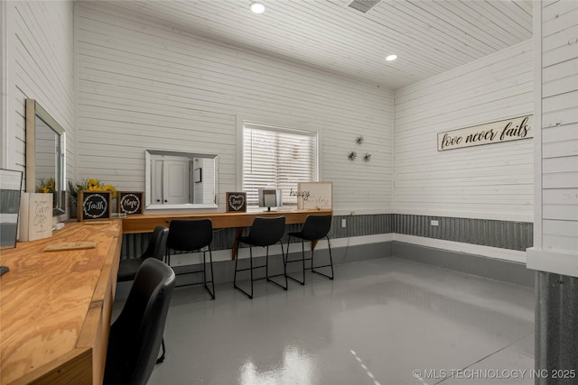 office space with a high ceiling, concrete flooring, and wooden ceiling