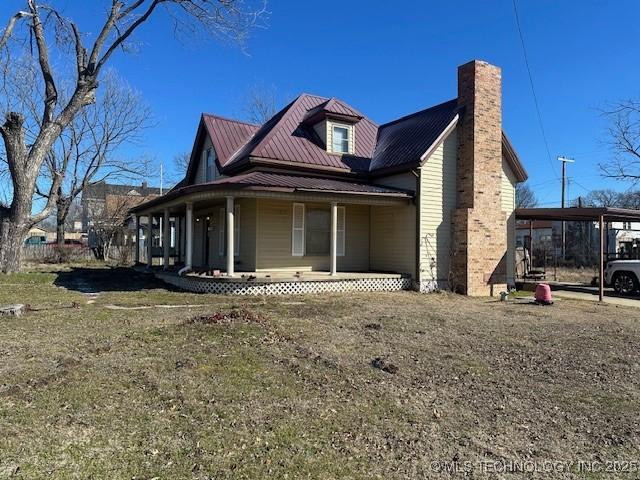 view of home's exterior with covered porch and a lawn