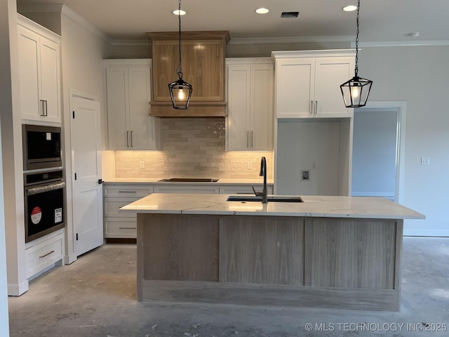 kitchen with pendant lighting, stainless steel oven, white cabinetry, and an island with sink