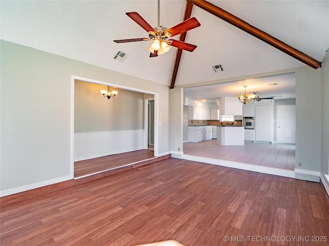 unfurnished living room with ceiling fan with notable chandelier, beam ceiling, high vaulted ceiling, and wood-type flooring