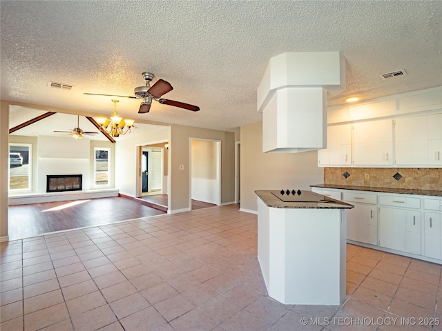 kitchen featuring ceiling fan with notable chandelier, white cabinets, backsplash, light tile patterned floors, and black electric cooktop