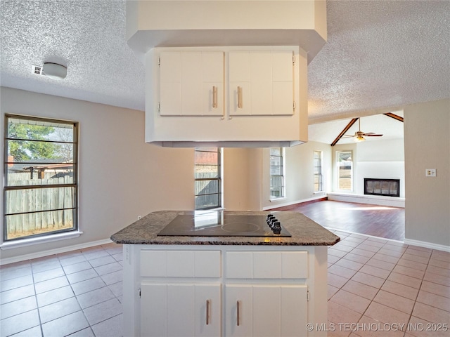 kitchen with dark stone countertops, white cabinetry, black electric stovetop, and light tile patterned flooring