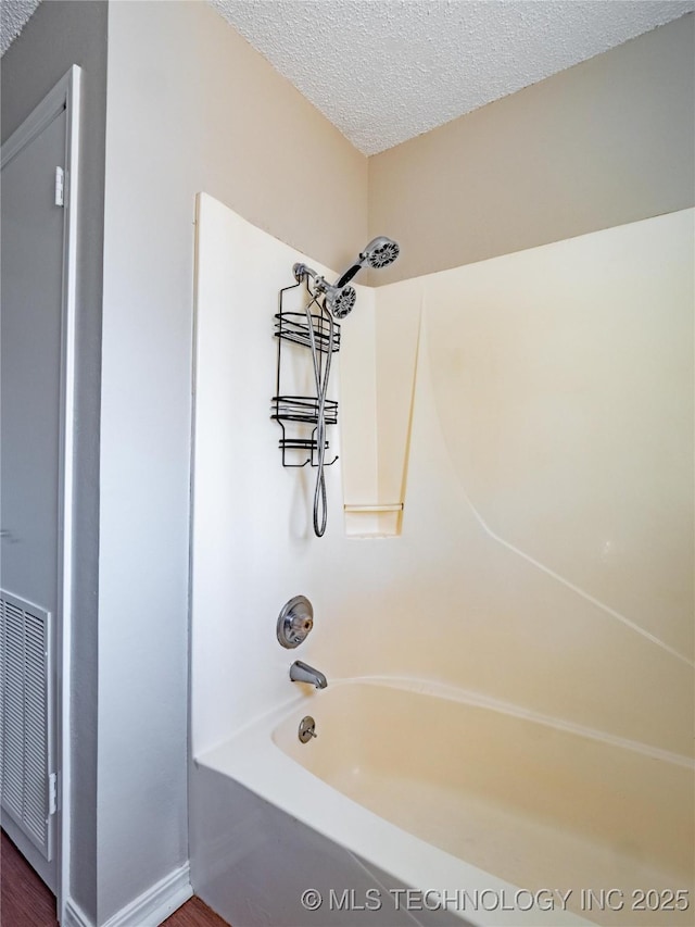 bathroom featuring shower / bathtub combination and a textured ceiling