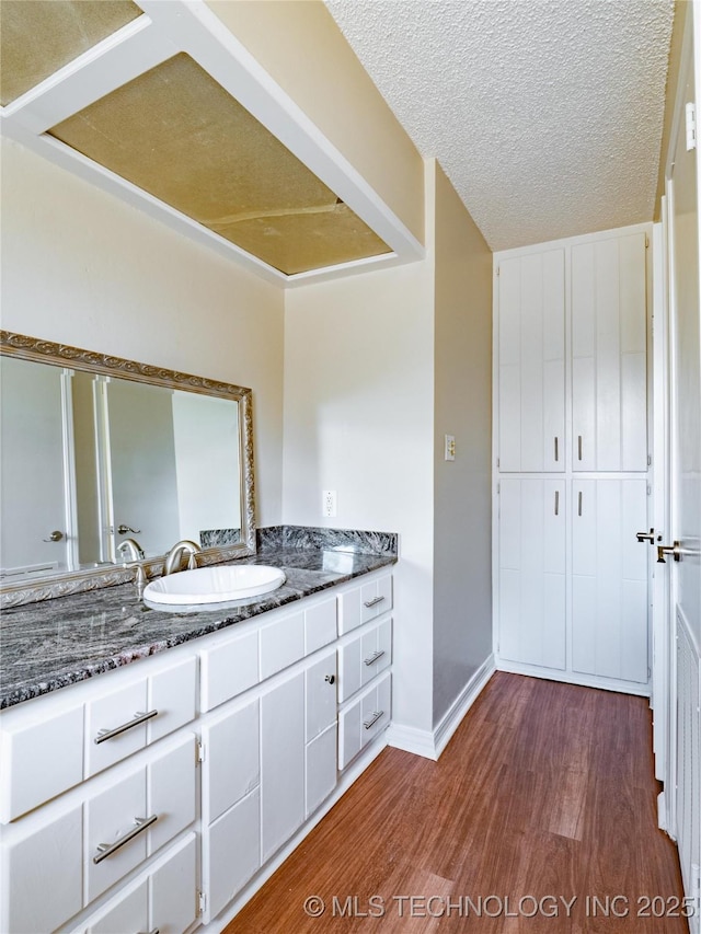 bathroom with wood-type flooring, vanity, and a textured ceiling