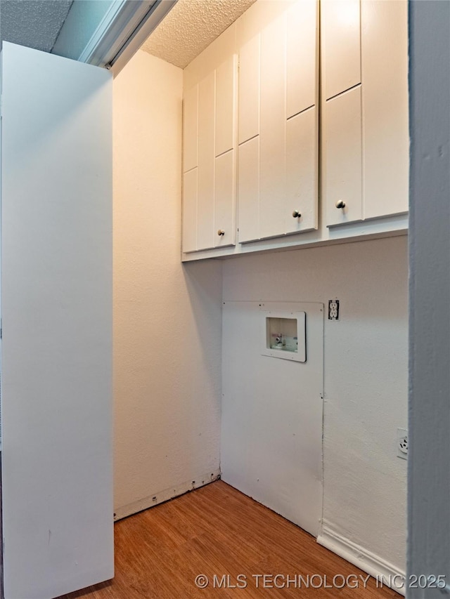 washroom featuring a textured ceiling, cabinets, light hardwood / wood-style flooring, and washer hookup