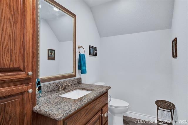 bathroom featuring vanity, toilet, and lofted ceiling