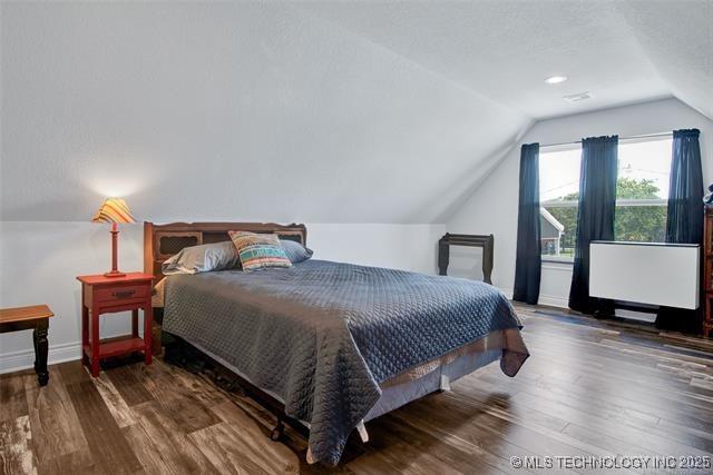 bedroom featuring dark hardwood / wood-style flooring and lofted ceiling