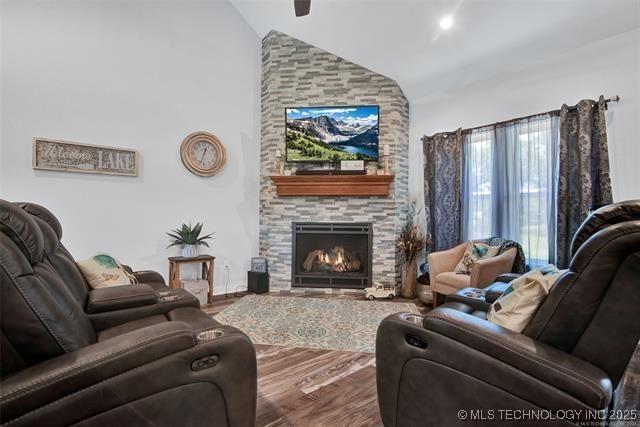 living room featuring wood-type flooring, lofted ceiling, and a large fireplace