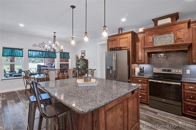 kitchen featuring a kitchen bar, pendant lighting, stainless steel appliances, and a kitchen island