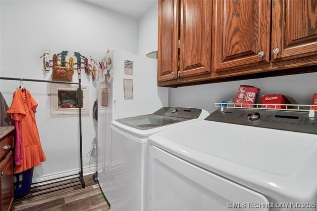 laundry room featuring cabinets, dark hardwood / wood-style floors, and washing machine and clothes dryer