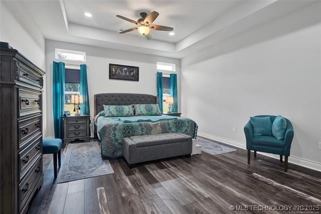 bedroom featuring ceiling fan, dark hardwood / wood-style floors, and a tray ceiling