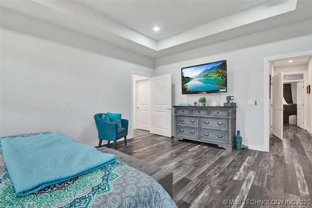 bedroom with dark wood-type flooring and a raised ceiling