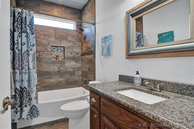 full bathroom featuring shower / bath combo with shower curtain, toilet, and vanity