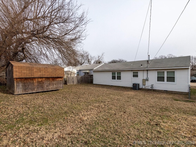 rear view of house featuring central AC, a yard, and a storage unit