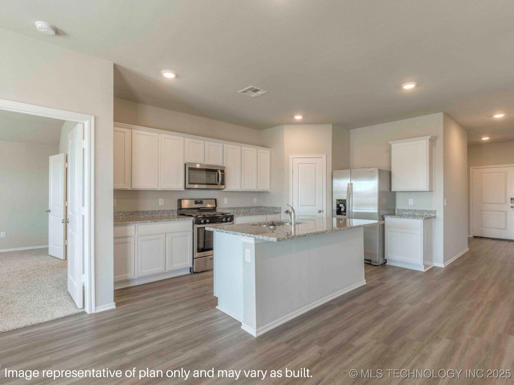 kitchen with a kitchen island with sink, white cabinetry, and stainless steel appliances