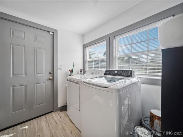 clothes washing area featuring separate washer and dryer, light hardwood / wood-style flooring, and a healthy amount of sunlight