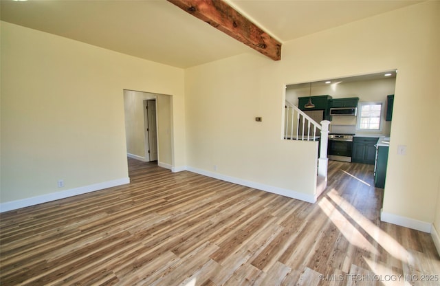 unfurnished living room featuring hardwood / wood-style floors and beam ceiling