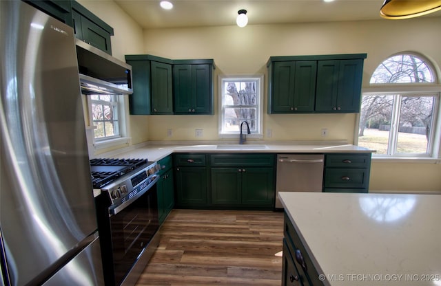 kitchen with sink, stainless steel appliances, green cabinets, and dark hardwood / wood-style floors