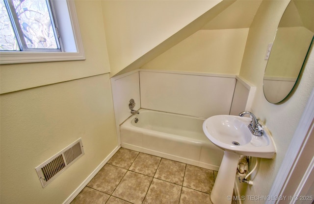 bathroom with a tub, sink, and tile patterned floors