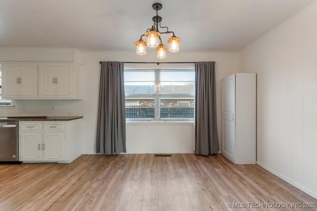 unfurnished dining area with light hardwood / wood-style floors and a notable chandelier