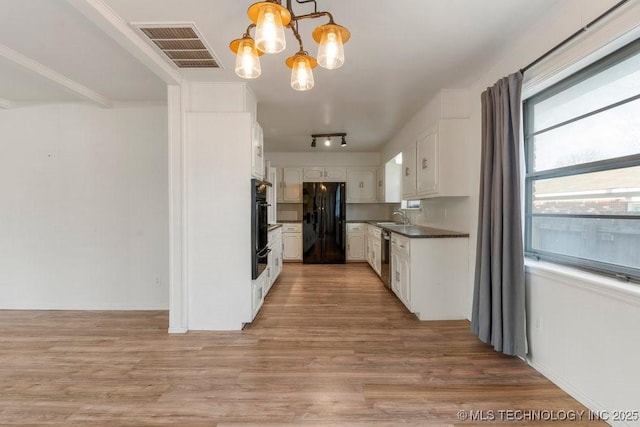 kitchen with black appliances, white cabinets, sink, light hardwood / wood-style flooring, and pendant lighting