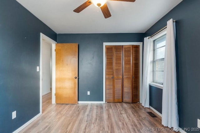 unfurnished bedroom featuring ceiling fan, a closet, and light wood-type flooring