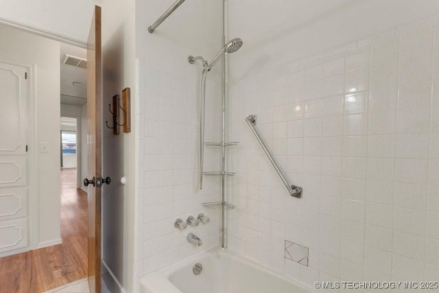 bathroom with hardwood / wood-style floors and tiled shower / bath combo