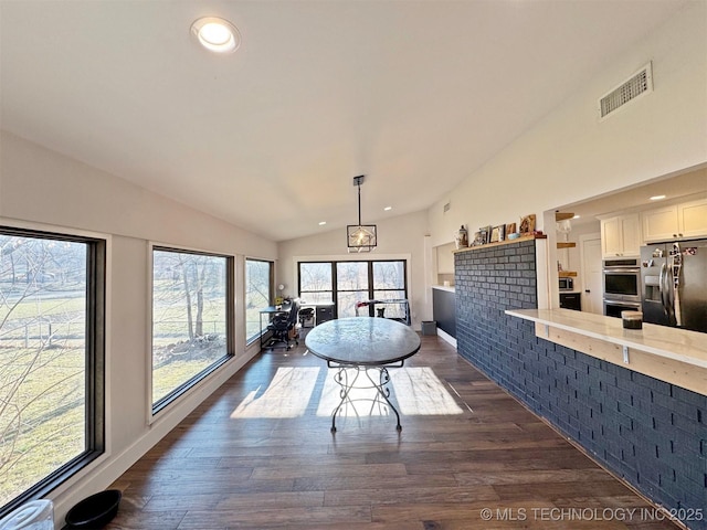 unfurnished dining area featuring vaulted ceiling and dark hardwood / wood-style flooring