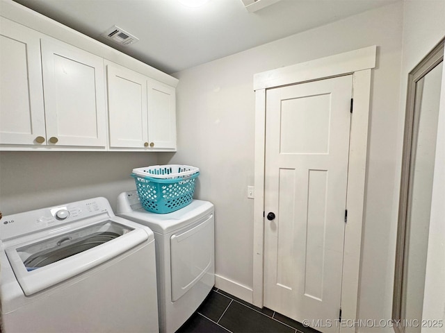 laundry area with dark tile patterned flooring, cabinets, and separate washer and dryer