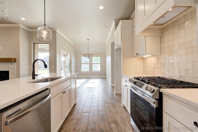 kitchen with sink, white cabinets, appliances with stainless steel finishes, and pendant lighting