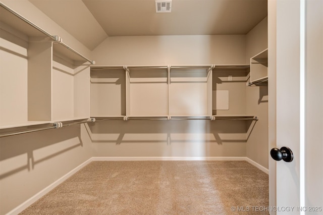 walk in closet with light carpet and vaulted ceiling