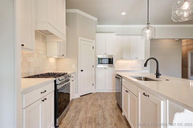 kitchen with hanging light fixtures, sink, white cabinets, light hardwood / wood-style flooring, and stainless steel appliances