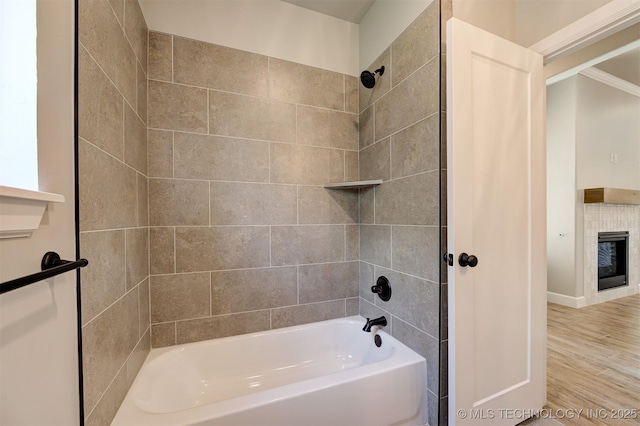 bathroom with a tiled fireplace and tiled shower / bath