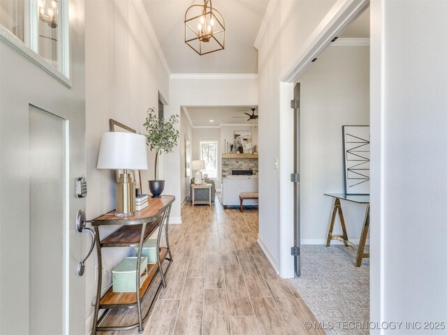 7113 E Princeton St, Broken Arrow, OK 74014 - entryway with ornamental molding, light wood-type flooring, a chandelier, and a fireplace
