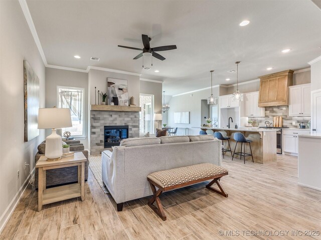 7113 E Princeton St, Broken Arrow, OK 74014 - living area featuring crown molding, light wood-style flooring, a ceiling fan, a brick fireplace, and recessed lighting