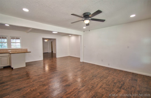 unfurnished living room with ceiling fan, a textured ceiling, dark hardwood / wood-style floors, and beam ceiling